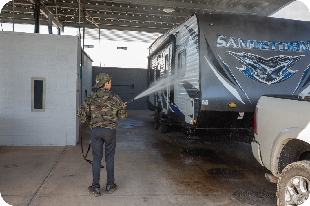 Easy-access RV wash stations available at Carefree Covered RV Storage Person power washing an RV at Carefree’s on-site self-service wash area