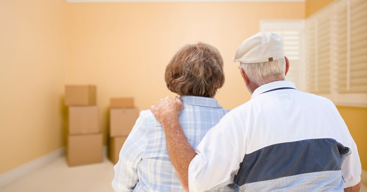 A picture of an elderly couple in an empty room with boxes