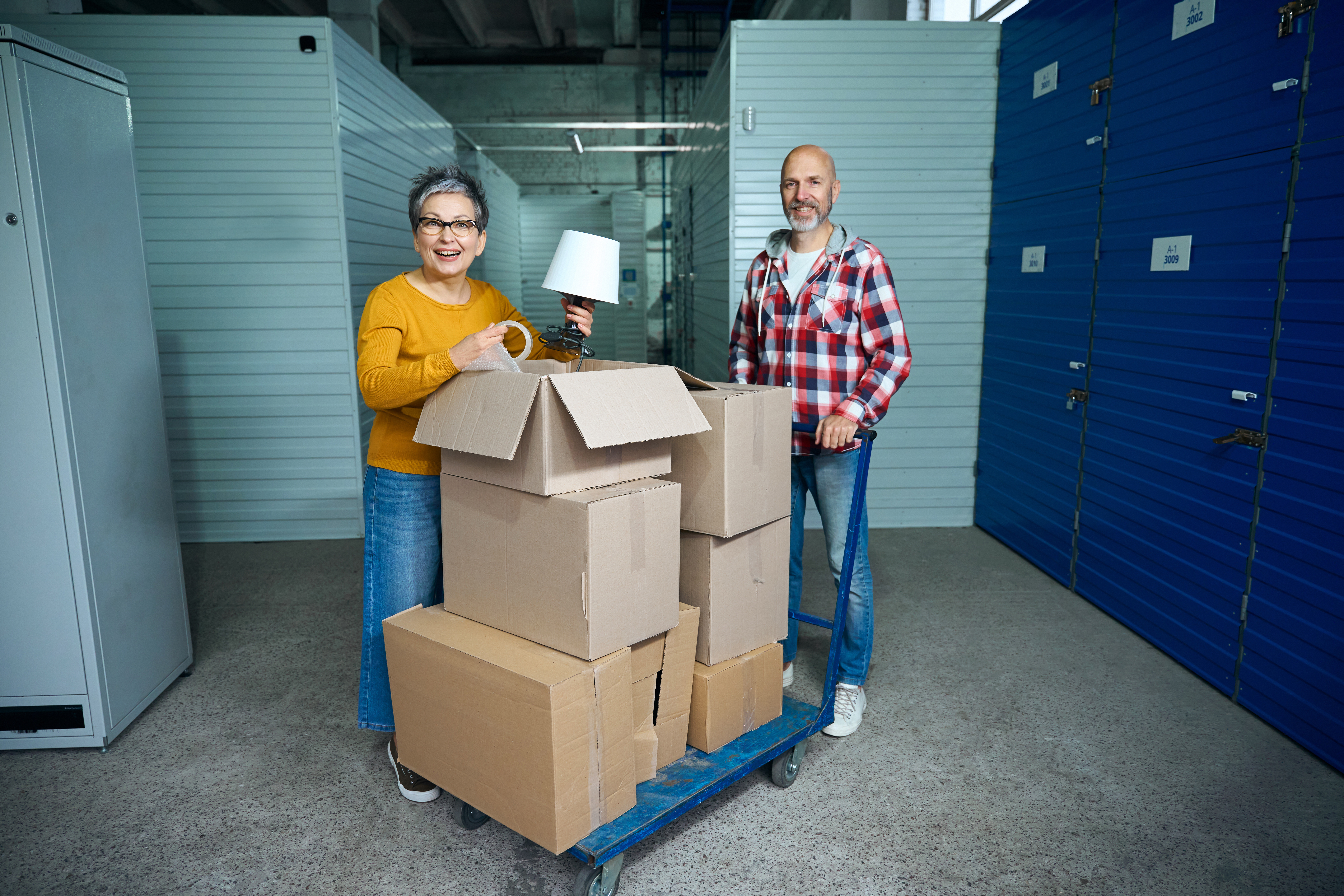 Woman and man standing by boxes in a storage facility. 
