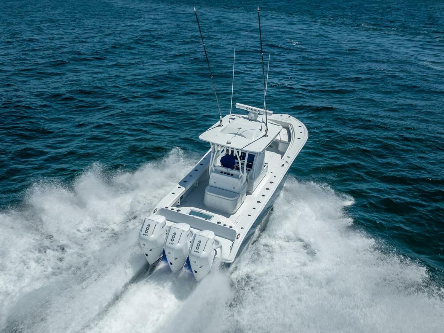 Performance this exhilarating deserves protection this elite. High-performance white center console sportfishing yacht with quadruple Yamaha 400 V10 outboard engines powering through open ocean, viewed from above with Garmin radar on hardtop tower