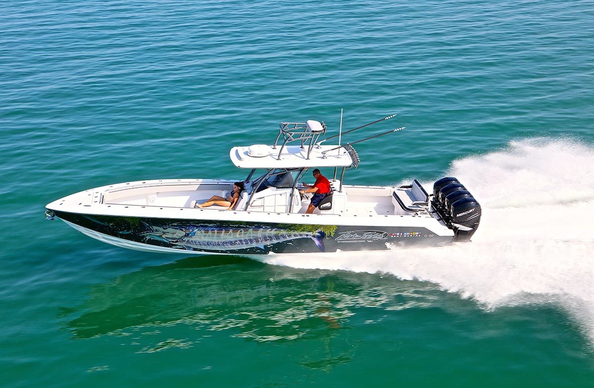 High-performance center console sportfishing yacht with triple Mercury outboards speeding across turquoise open water, featuring custom marlin hull wrap and upper helm station
