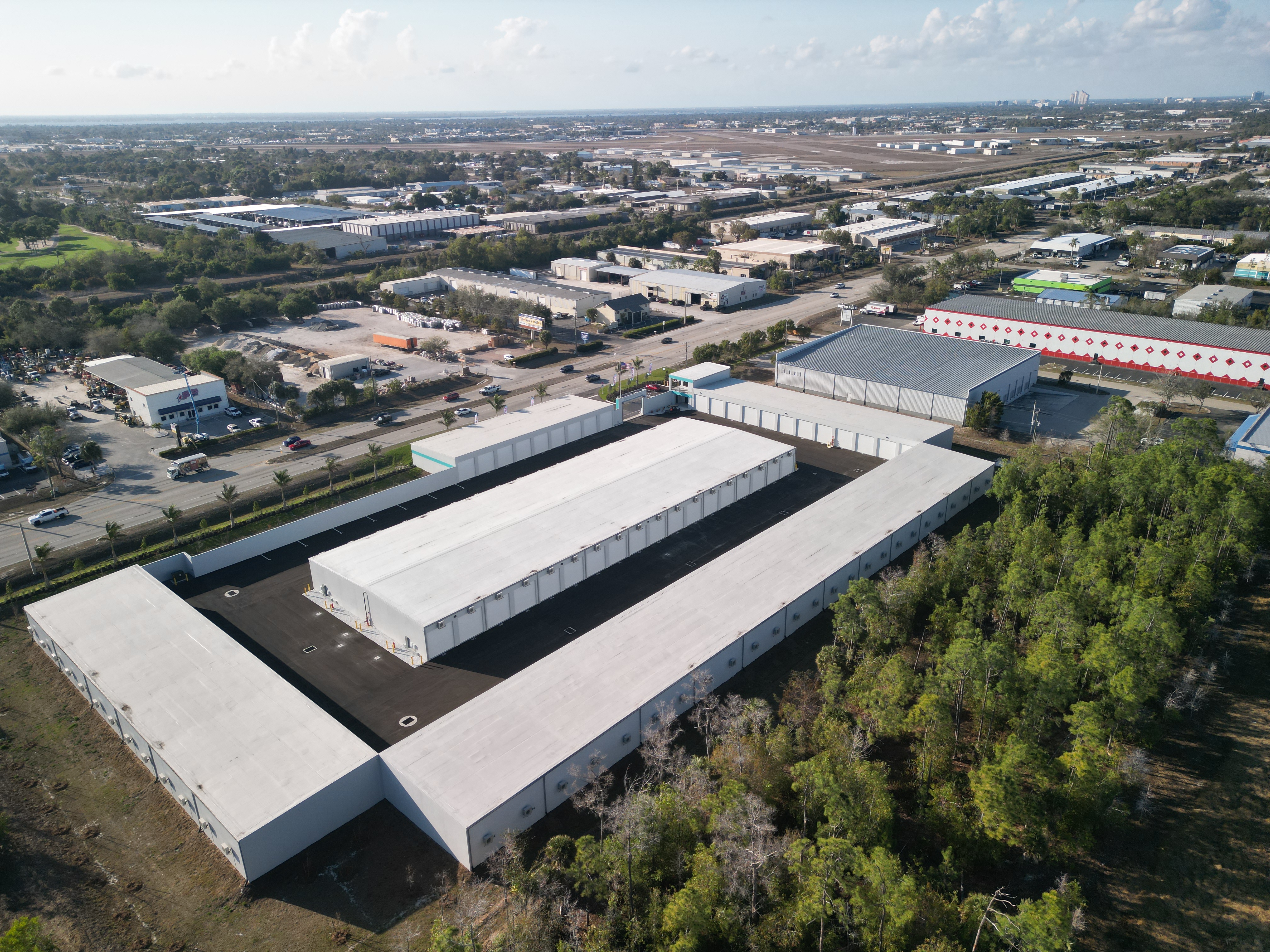 Drone aerial view of MetroMaxx RV and Boat Storage facility in Fort Myers, Florida showing climate-controlled private storage units, wide concrete drive aisles, and nearby Page Field Airport.