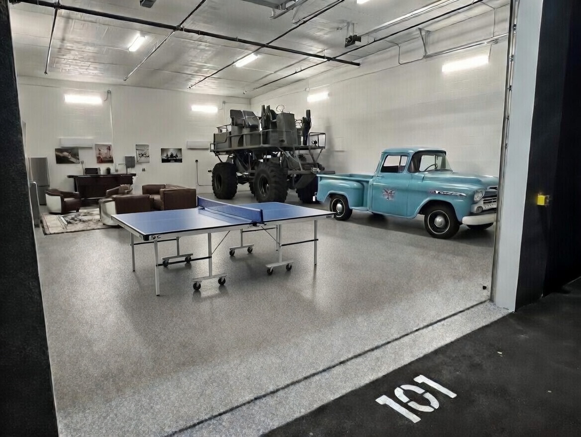 Luxury man cave style storage unit with epoxy flake floors, seating area, vehicles, and climate control inside MetroMaxx RV and Boat Storage in Fort Myers.