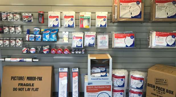boxes, plastic covers, tape, plastic wrap and locks displayed for purchase Packing supplies and locks available for purchase