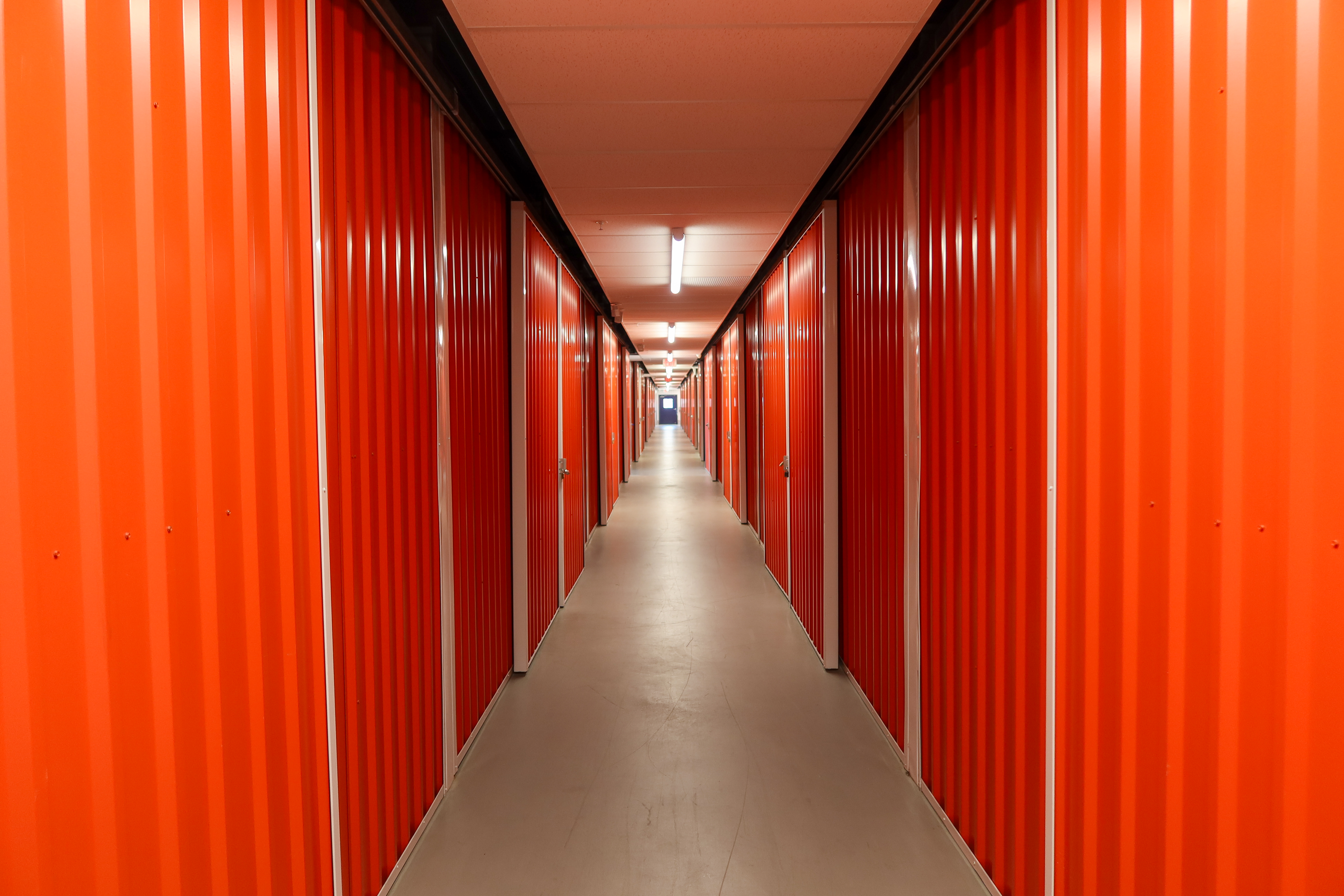 Clean indoor hallway with orange self-storage units at Dependable Storage Jefferson Louisiana