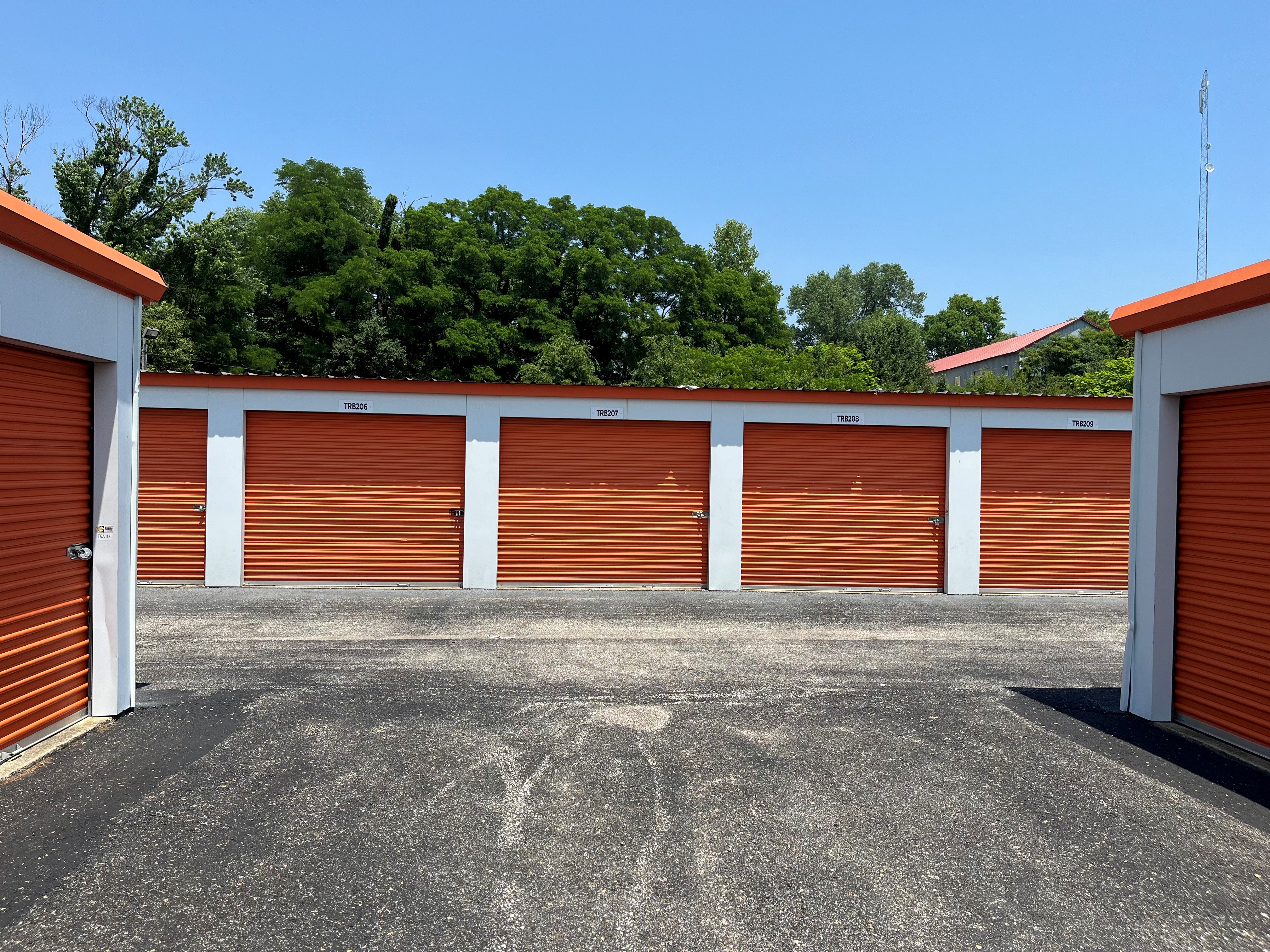 Well-maintained storage units with white doors on Truman Rd in Jasper, featuring broad, paved driveways for convenient drive-up access.