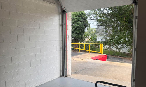 Photo taken from inside of loading dock showing loading dock and trees in the background