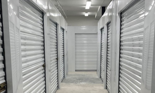 Interior photo showing storage units, rolling security doors, walls and all paint is grey.